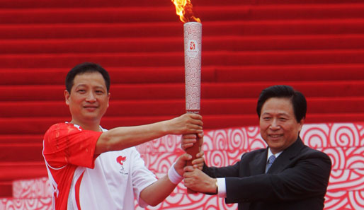 Der siebenfache Badminton-Weltmeister Yang Yang übergibt die Fackel an den Parteifunktionär Liang Baohua
