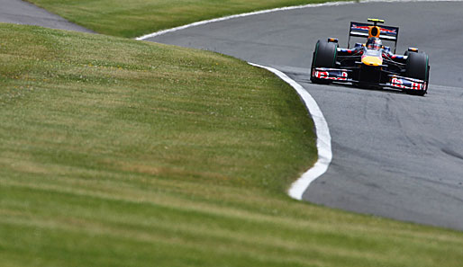 Sebastian Vettel ist in seinem Roten Bullen auf dem grauen Asphalt zwischen den grünen englisch Wiesen der schnellste Mann auf dem Kurs