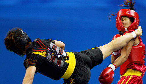 Ka-rumms! Beim Wushu-Contest der Asian Games gibt E Meidie (l.) ihrer Gegnerin Thi Bich Nguyen aus Vietnam so hart auf die Zwölf, dass der Helm auf halb acht hängt