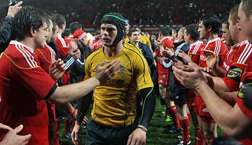 Rugby: Walk of Shame. Berrick Barnes (M.) schreitet nach Australiens historischer Niederlage gegen Munster angefressen durch die Spalier stehenden Munster-Spieler