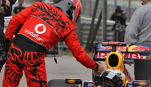 McLaren sieht rot. Jenson Button präsentierte der Welt bei seiner Gratulation an Sebastian Vettel das China-Design der neuen McLaren-Overalls