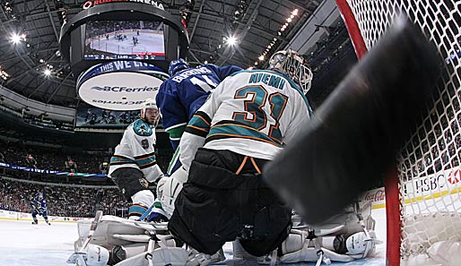 Vorsicht! Da kommt ein Puck geflogen! Chris Higgins von den Vancouver Canucks überwindet in den NHL-Playoffs Sharks-Goalie Antti Niemi (r.)