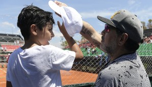 In diesem Jahr hat Maradona sogar seinen Enkel im Schlepptau. Ein Kopfschutz ist bei der prallen Sonne auf jeden Fall angebracht