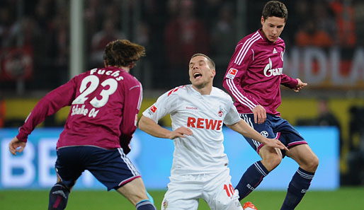 Die Schalker Christian Fuchs (l.) und Julian Draxler (r.) legen Lukas Podolski (M.) im Zweikampf