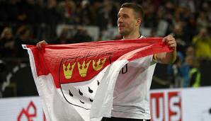 Lukas Podolski mit der Kölschen-Flagge in der Hand nach einem Länderspiel