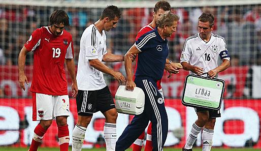 Klaus Eder wurde von Miroslav Klose und Mesut Özil gestützt während Philipp Lahm den Koffer trug