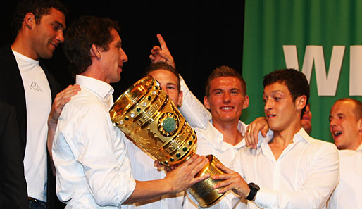 Ehrfürchtig übernimmt Mesut Özil (r.) den Pokal von Frank Baumann