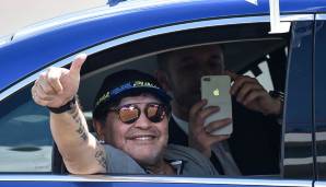 Seine gute Laune hat er definitiv mitgebracht, Maradona kommt aus dem Grinsen gar nicht mehr heraus. Sein Mitfahrer findet die Fotografen allerdings interessanter.