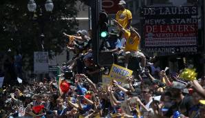 Kein Platz mehr am Straßenrand? Kein Problem! Die Fans der Warriors erklimmen kurzerhand einfach die Ampeln, um ganz nah dran zu sein.