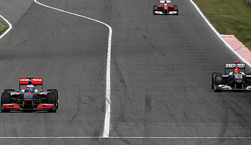 Die Szene des Rennens: Michael Schumacher (l.) geht bei Buttons Boxenausfahrt am Briten vorbei und gewinnt eine Position