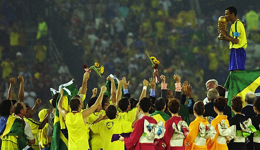Die Selecao feiert und kann sich ab sofort Rekord-Weltmeister nennen. Kapitän Cafu (r.) knutscht den Pokal, Trainer Scolari (l.) hat sich in eine Flagge gehüllt