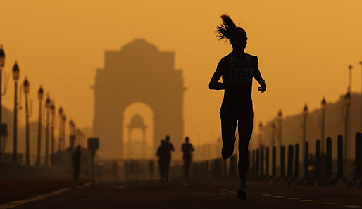 Eine einsame Läuferin beim Damen-Marathon in Neu-Dehli. Im Hintergrund schimmert das berühmte Indische Tor im Regierungsviertel Indiens