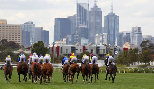 Nette Aussicht: Im Zuge des Crown Oaks Day in Australien galoppieren die Jockeys in Richtung der Skyline von Melbourne