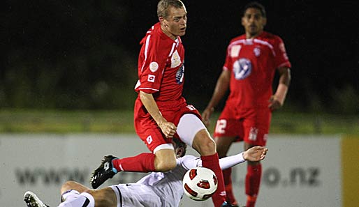 Kiwi-Kick in Auckland: Martin Bullock (rot) wird im Freundschaftsspiel zwischen Waitakere United und der Nationalmannschaft von David Mulligan ordnungsgemäß abgegrätscht