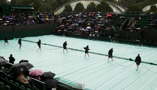 Nein, wir sind hier nicht beim Eishockey. Was ein kleines bisschen nach Eishalle aussieht, ist ein Wimbledon-Court im Regenmantel. Die Fans warten...