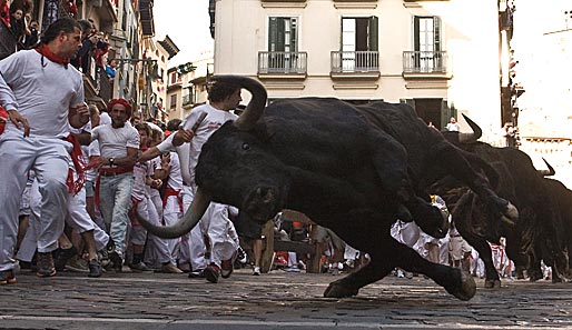 Zu schnell gehetzt! Beim Stierrennen in Pamplona verliert ein Bulle die Balance. Der Kameramann möchte man da wohl nicht sein