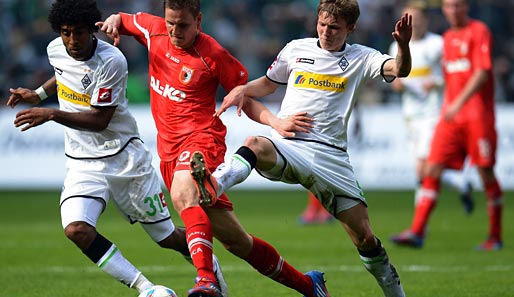 Dann wurde auch Fußball gespielt: Augsburgs Torsten Oehrl tankt sich gleich durch zwei Gegenspieler durch