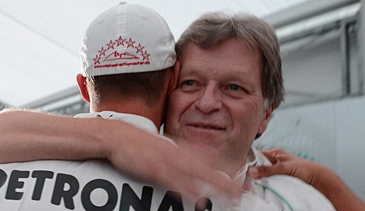 Sportchef Norbert Haug (r.) umarmt nach der Pressekonferenz Michael Schumacher (l.)