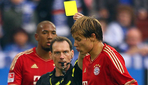 Florian Meyer zeigt Bayern-Verteidiger Holger Badstuber im Spiel auf Schalke die Gelbe Karte