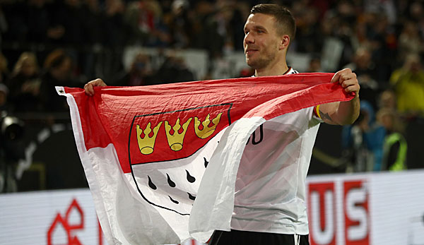 Lukas Podolski nach einem Spiel für die Nationalmannschaft mit der Kölner Flagge in der Hand