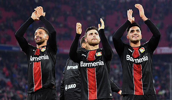 Karim Bellarabi, Kevin Volland und Nadiem Amiri feiern zusammen mit den Leverkusener Fans.