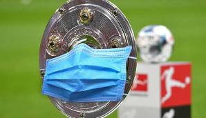 Die Meisterschale mit Atemschutz-Maske: Fußball ist in Zeiten des Coronavirus zum Politkum geworden - besonders der Liga-Neustart Mitte Mai.