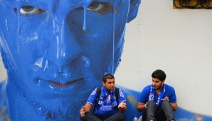 Zwei Chelsea-Fans diskutieren vor einem Werbe-Plakat des FC Chelsea mit Eden Hazard