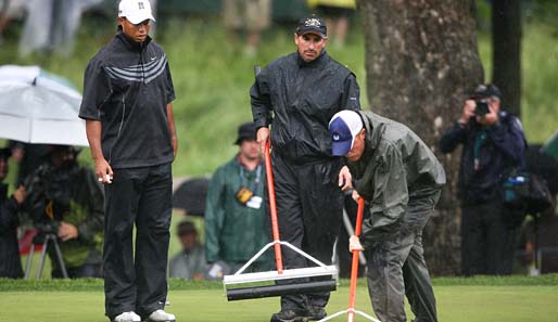 Tag 1: Tiger Woods (l.) beobachtet die Greenkeeper beim Entwässern der Grüns
